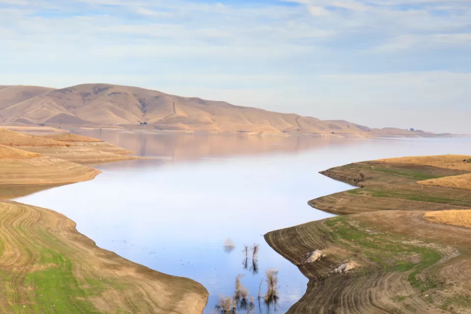 A barren landscape surrounds a reservoir well below its capacity.